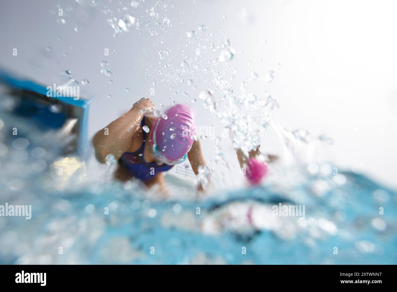 Vista subacquea di un nuotatore con gli occhiali di protezione e di un berretto da nuoto che alimenta l'acqua con un forte colpo freestyle. Foto Stock