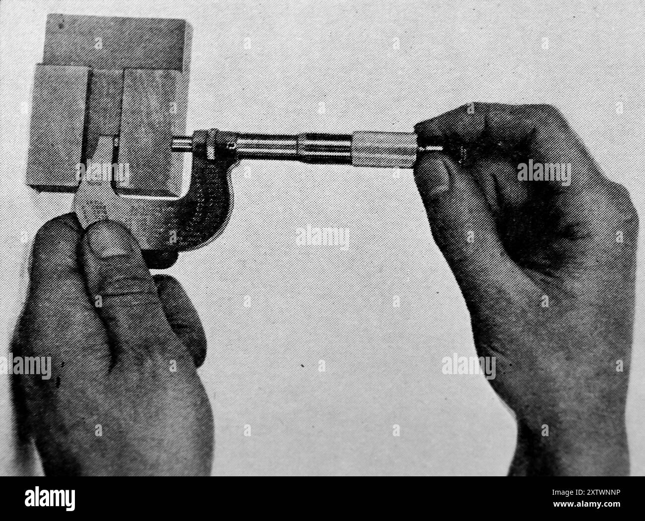 Un micrometro in uso. Questa fotografia proviene da un'ampia selezione di illustrazioni ingegneristiche e foto, principalmente non attribuite, che sono state originariamente pubblicate nel 1936. Le dimensioni e la qualità degli originali variano notevolmente. Foto Stock