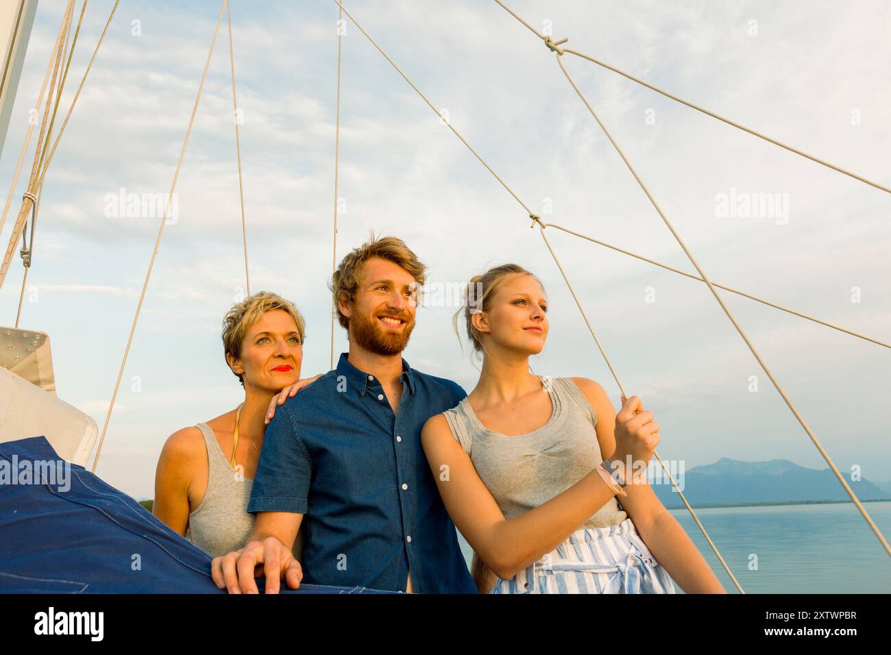 Tre persone si godono un tranquillo giro in barca al tramonto, con uno sfondo di un mare calmo e un cielo limpido. Foto Stock