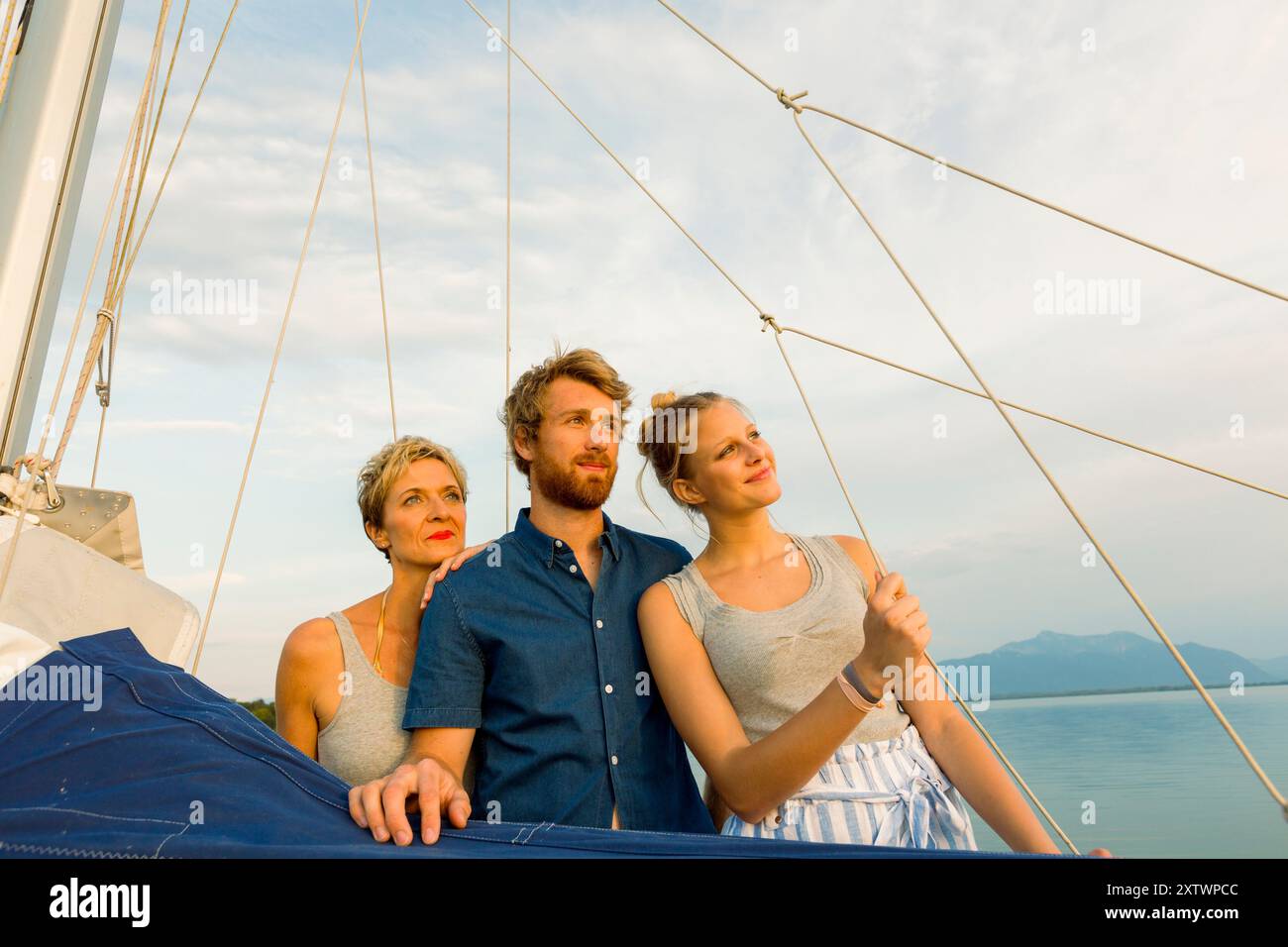 Tre persone si stanno godendo un tranquillo giro in barca con una vista del cielo aperto e delle acque calme durante il tramonto. Foto Stock