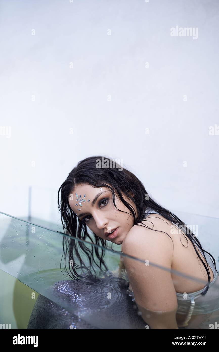Una sirena con capelli scuri guarda intensamente da sotto la superficie dell'acqua in un acquario. Foto Stock
