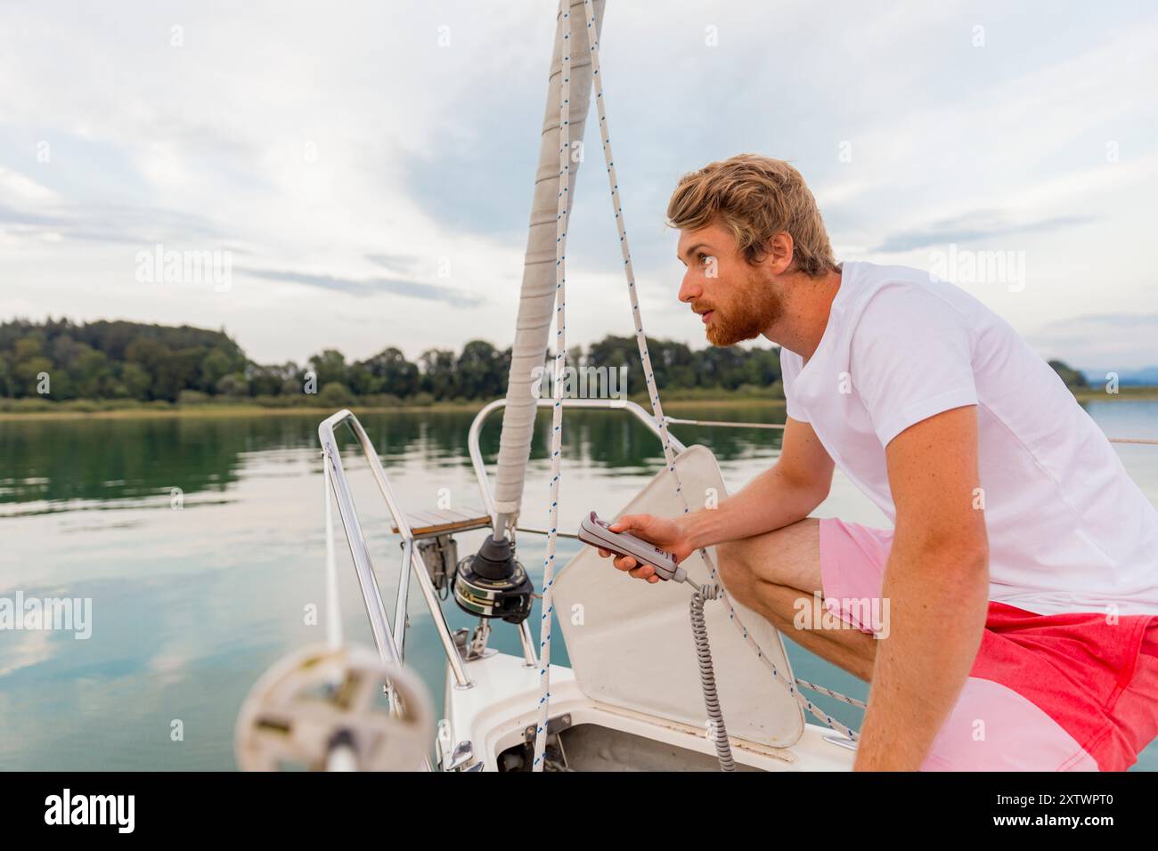 Uomo che guida una barca con attenzione e attenzione su un lago calmo durante una giornata serena. Foto Stock