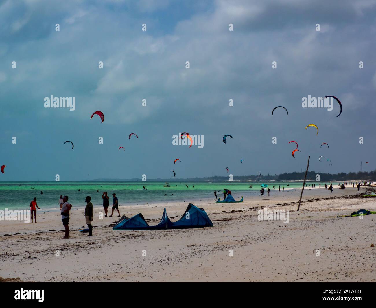 Zanzibar, Tanzania - 20 gennaio 2021: Kitesurf e paracadute colorati sulle acque blu dell'oceano Indiano vicino alla spiaggia di surf a P Foto Stock