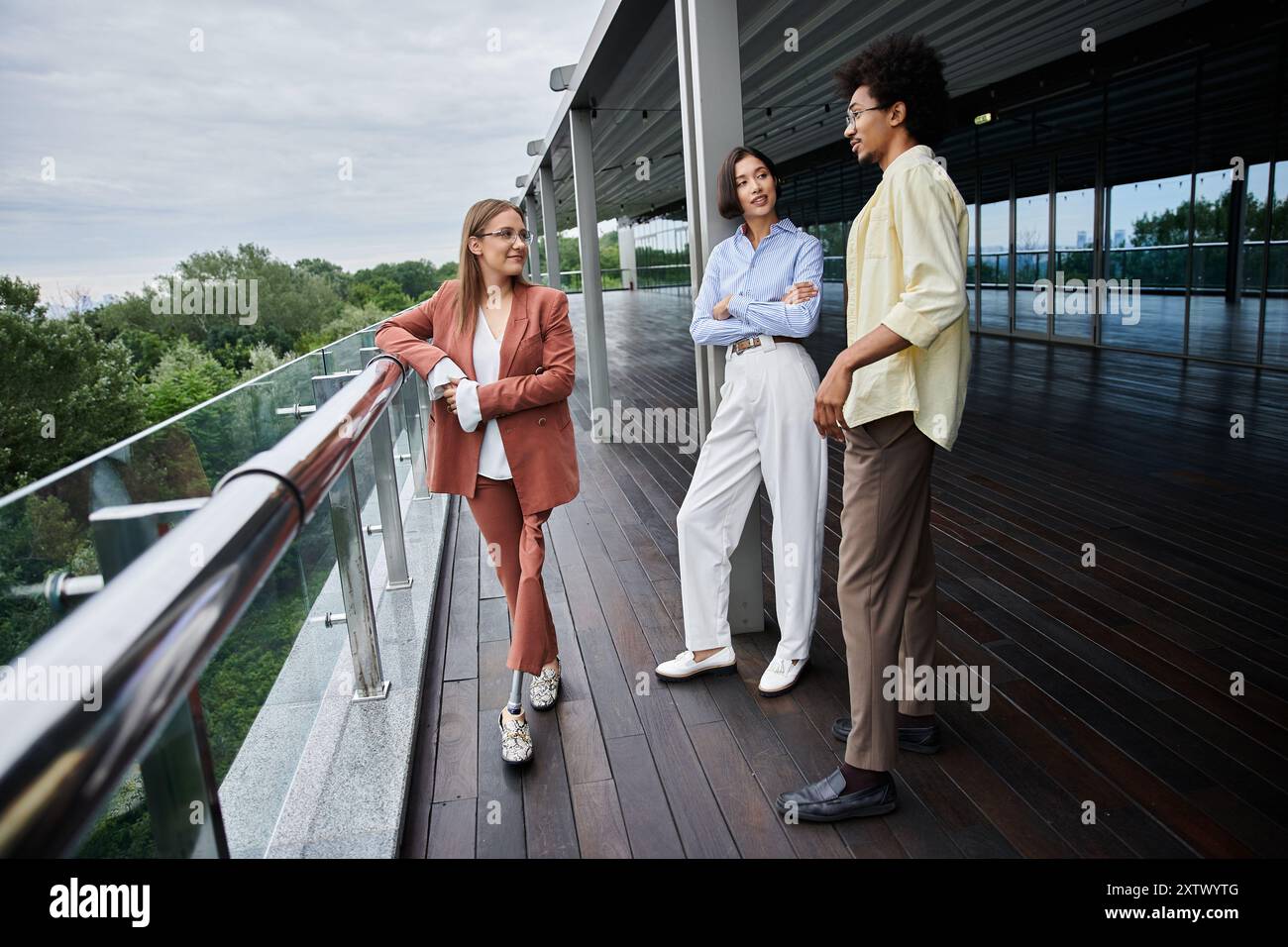I colleghi di diverse razze chiacchierano su un tetto, evidenziando la diversità e l'inclusività sul posto di lavoro. Foto Stock
