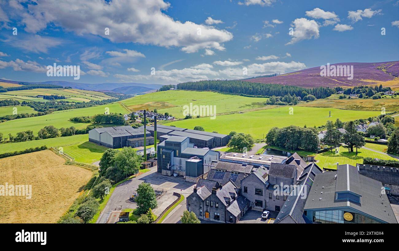 La distilleria Glenlivet Moray Scotland un cielo estivo blu sopra edifici magazzini e colline coperte di erica Foto Stock