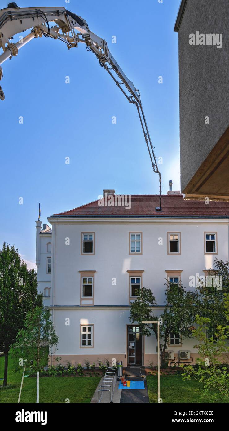 Calcestruzzo consegnato in un attico di una casa a Tulln da una pompa molto estesa e da un tubo flessibile attraverso una botola sul tetto, Austria Foto Stock