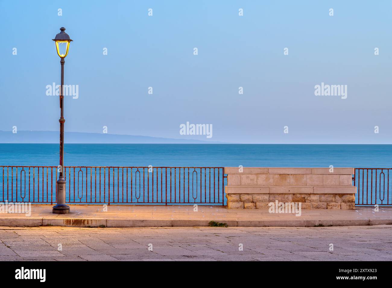 Semaforo e panca vuota all'alba vista a Trani, Italia Foto Stock