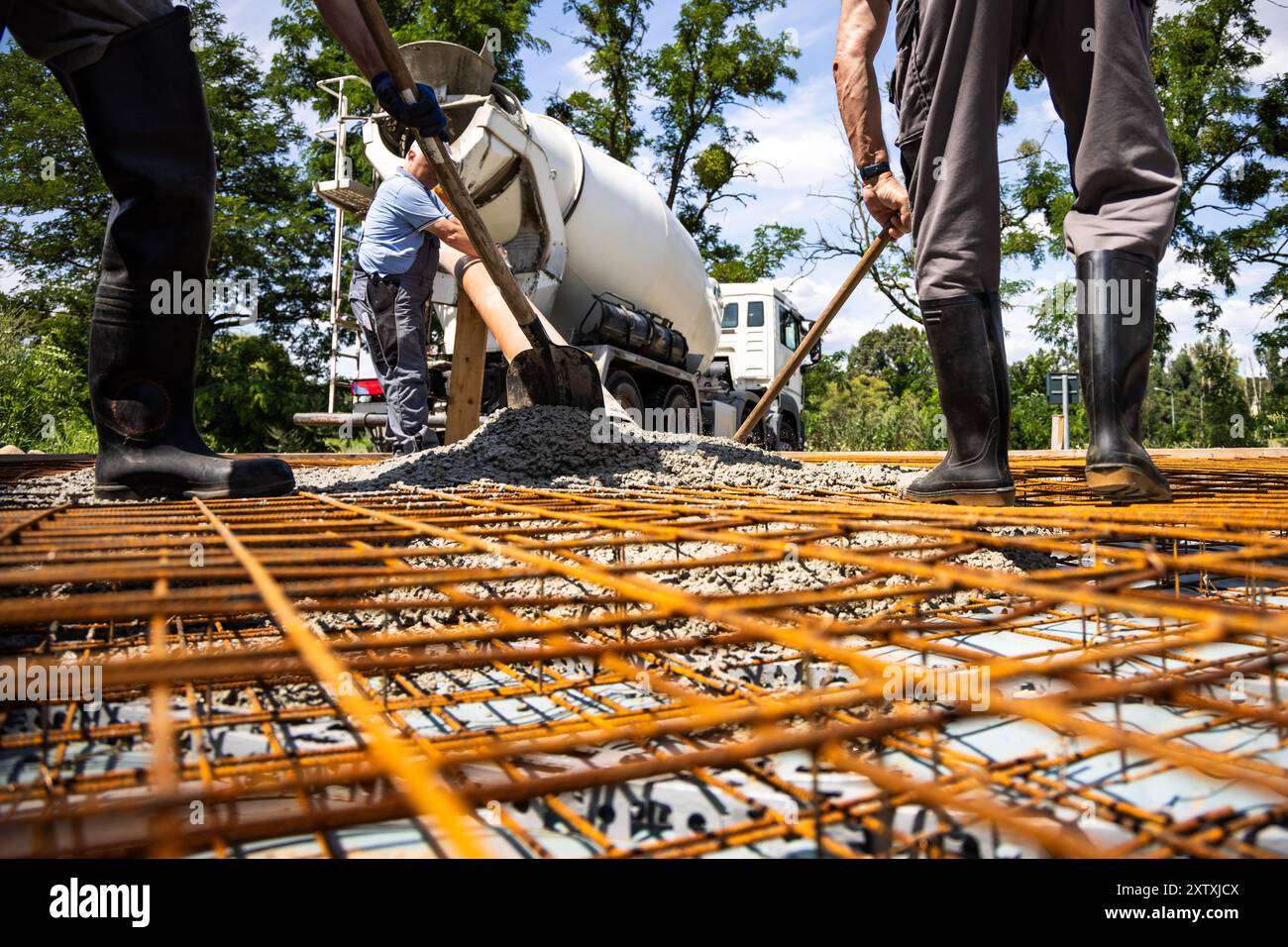 Versamento di calcestruzzo sulla struttura per armature per la costruzione di lastre di terreno Foto Stock