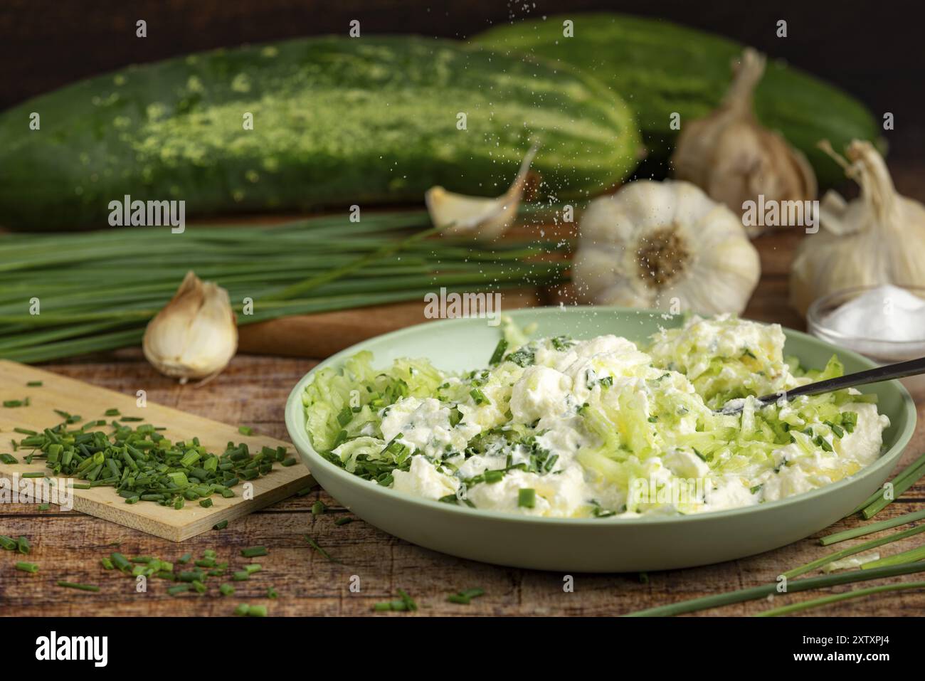Rappresentazione di un momento di preparazione, in cui il sale viene cosparso in un recipiente con un composto di panna e cetrioli Foto Stock