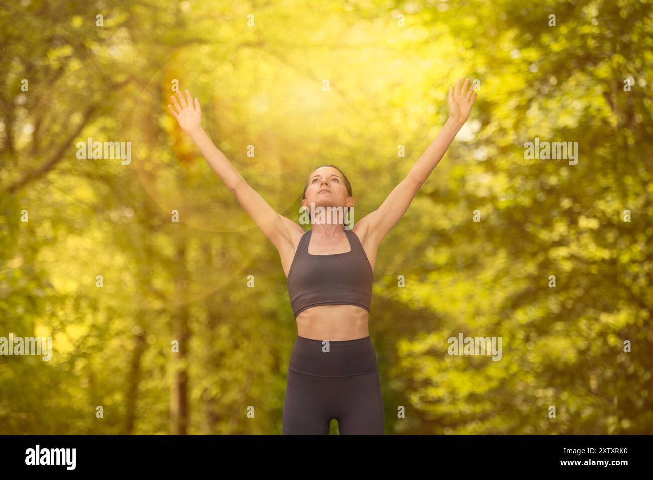 Atleta per adulti con le braccia alzate per festeggiare all'aperto, bagliore del sole. Foto Stock