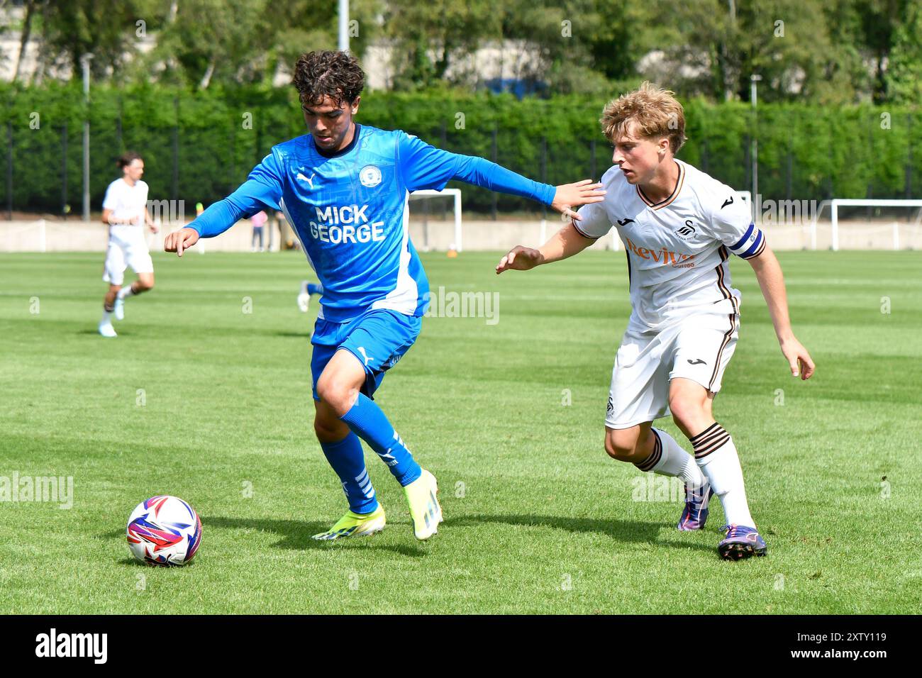 Landore, Swansea, Galles. 16 agosto 2024. Joseph Davies del Peterborough United (a sinistra) sotto la pressione di Callum Deacon di Swansea City durante la partita Under 18 Professional Development League tra Swansea City e Peterborough United al JOMA High Performance Centre di Landore, Swansea, Galles, Regno Unito il 16 agosto 2024. Crediti: Duncan Thomas/Majestic Media/Alamy Live News. Foto Stock