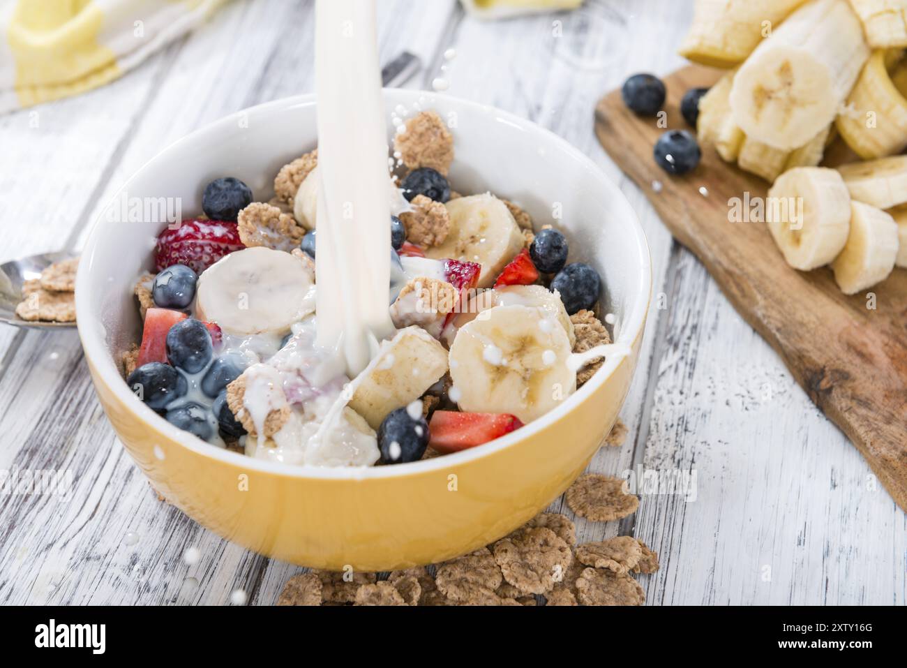 Corn flakes con frutta fresca e latte su un tavolo di legno Foto Stock