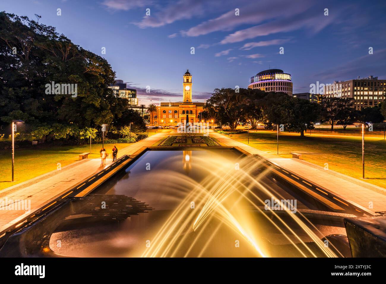 Fontana sfocata e piscina d'acqua nell'edificio del municipio della città di Newcastle al tramonto con illuminazione. Foto Stock