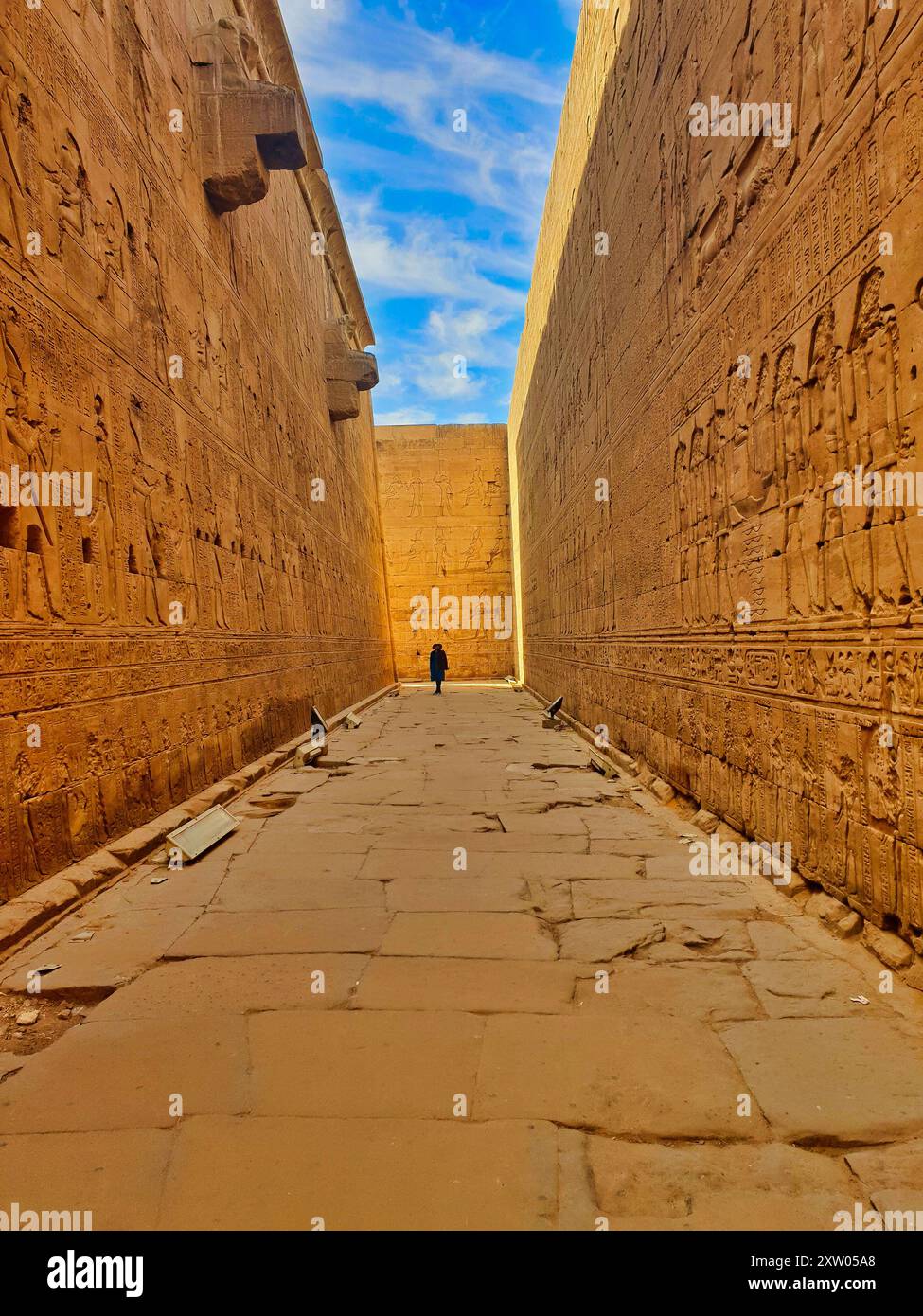 Un visitatore ammira i bassorilievi sulle intricate pareti di arenaria scolpite nel Tempio di Horus a Edfu costruito durante l'era tolemaica tra il 237 e il 57 a.C. vicino ad Assuan, in Egitto Foto Stock