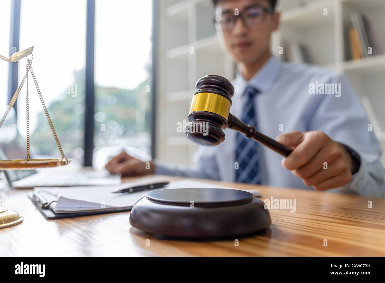 Chiudete la mano di un giudice maschio con un martelletto di corte che sta per colpire la sua base Foto Stock