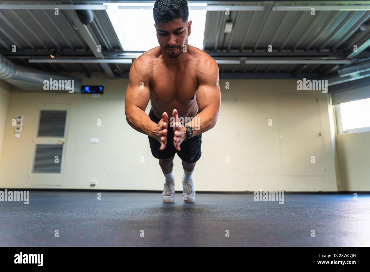 Uomo latino che fa push-up battendo le mani durante un allenamento Foto Stock