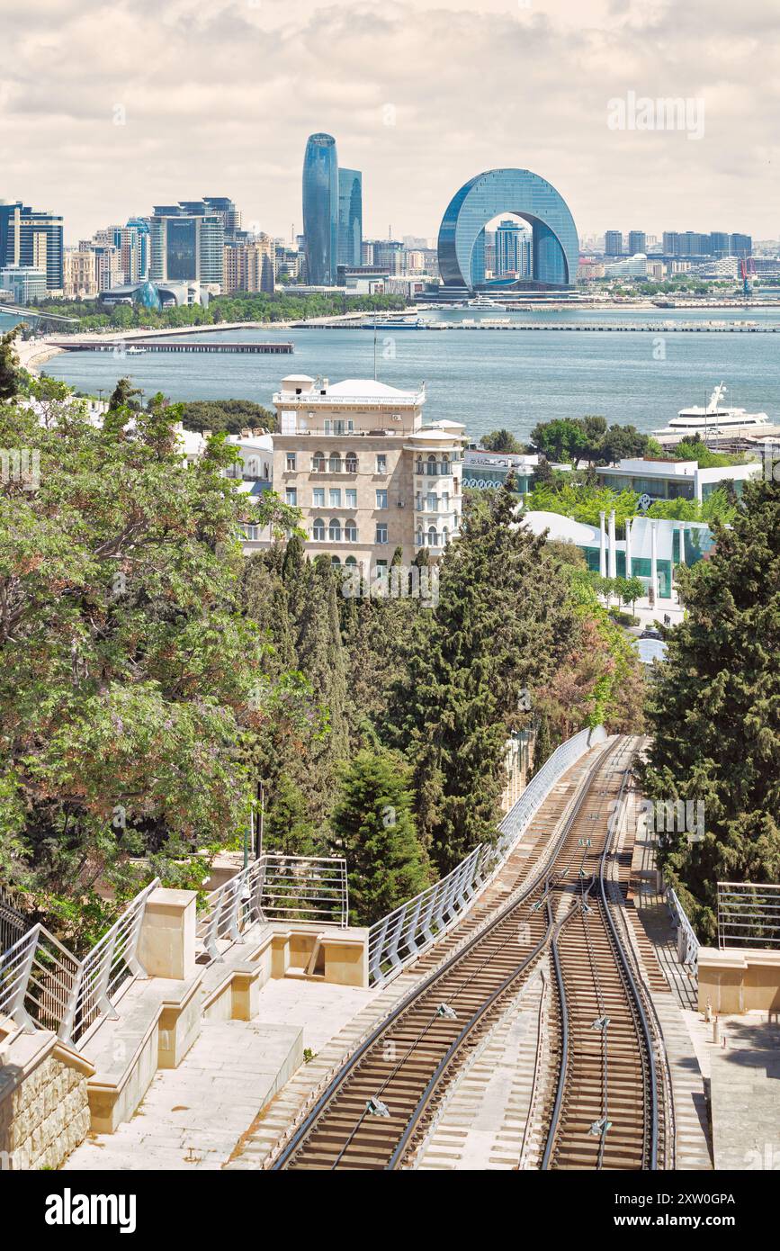 Veduta di Baku, Azerbaigian. In primo piano, la funicolare di Baku attraversa una lussureggiante veranda. . Sullo sfondo, lo skyline della città si estende attraverso il Mar Caspio Foto Stock