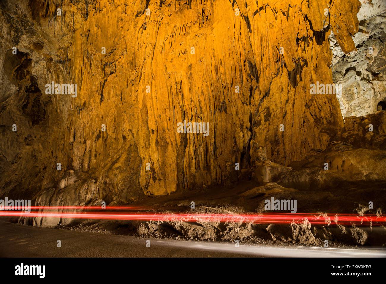 Veicolo che passa di fronte a una lapide nel tunnel naturale di la Cuevona, Cuevas, Asturias, Spagna. Foto Stock