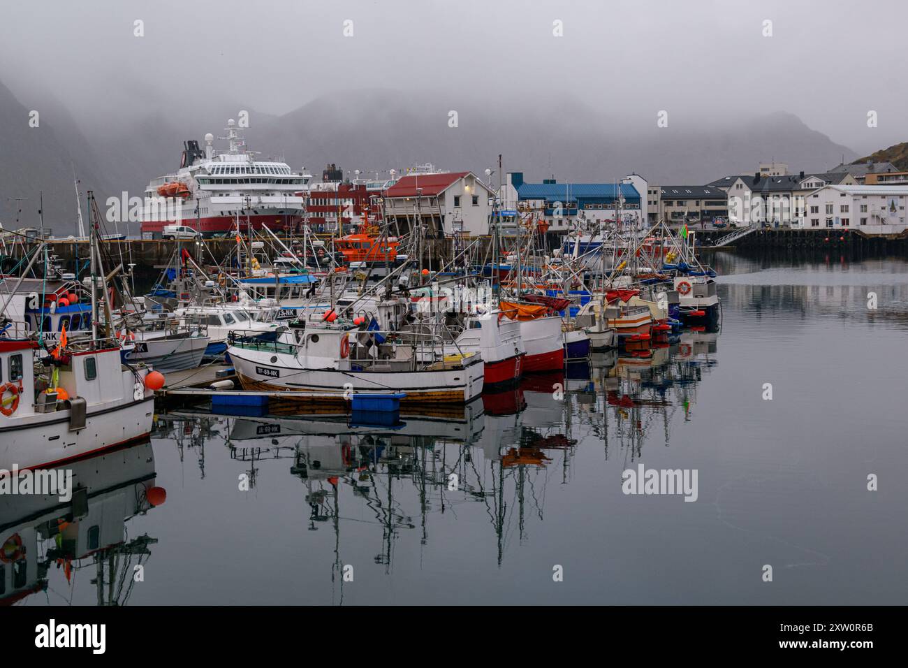 Vista invernale nebbiosa delle barche nel porto di Honningsvåg in Norvegia. Il traghetto Hurtigruten Nordlys attraccò sullo sfondo. Foto Stock