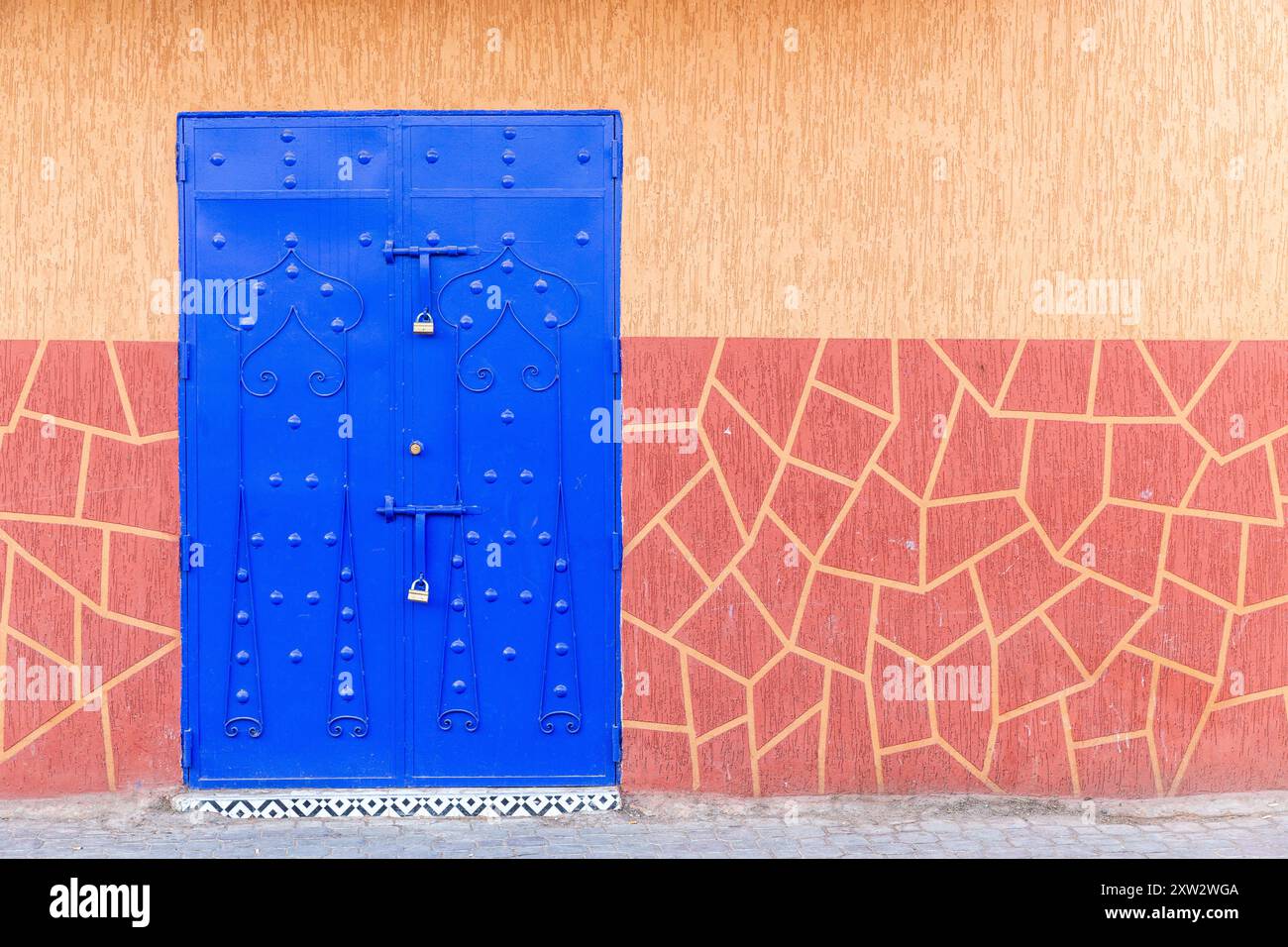 Porta di metallo blu su sfondo di una parete gialla con muratura dipinta Foto Stock