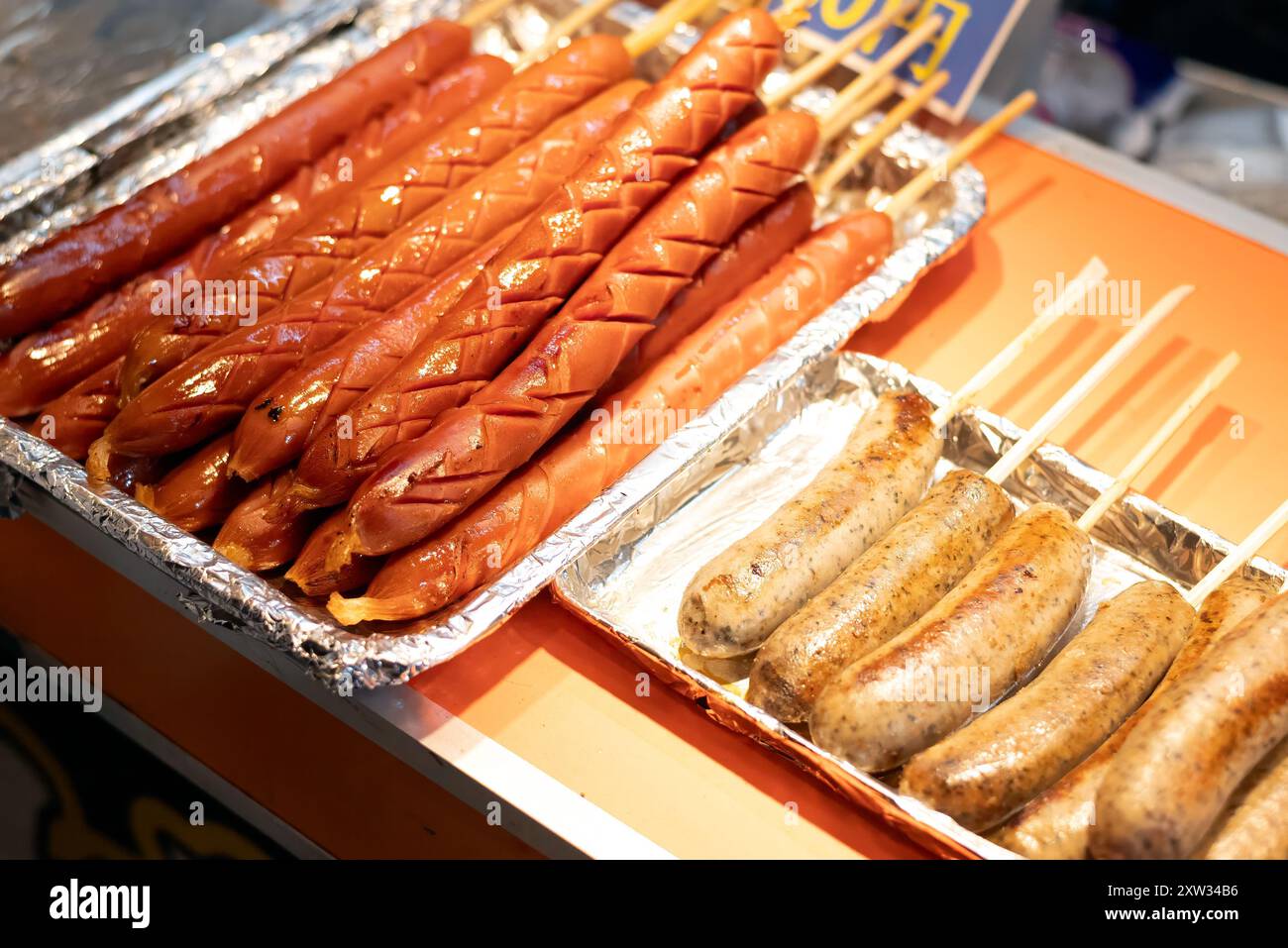 Salsicce lunghe e corte su spiedini in vendita in una bancarella di Street food. Foto Stock