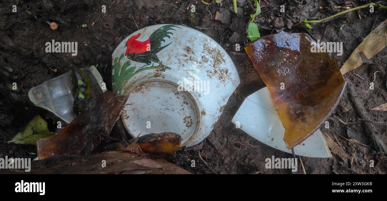 Recipiente in ceramica rotto con estrazione della torrefazione su un terreno sporco. Recipiente in ceramica rotto per terra. Foto Stock