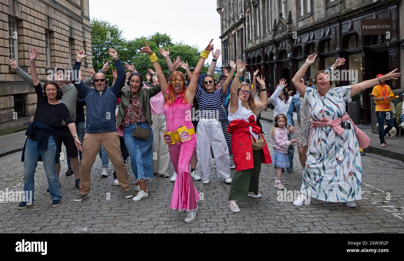 Centro di Edimburgo, Scozia, Regno Unito. 17 agosto 2024, Silent disco di Guru Dudu per tutte le età in pieno svolgimento guidato da Madame Cha Cha e qui i partecipanti indossano i copricapo ascoltando la musica che si dirige verso il Royal Mile. Credito: Arch White/alamy notizie dal vivo. Foto Stock