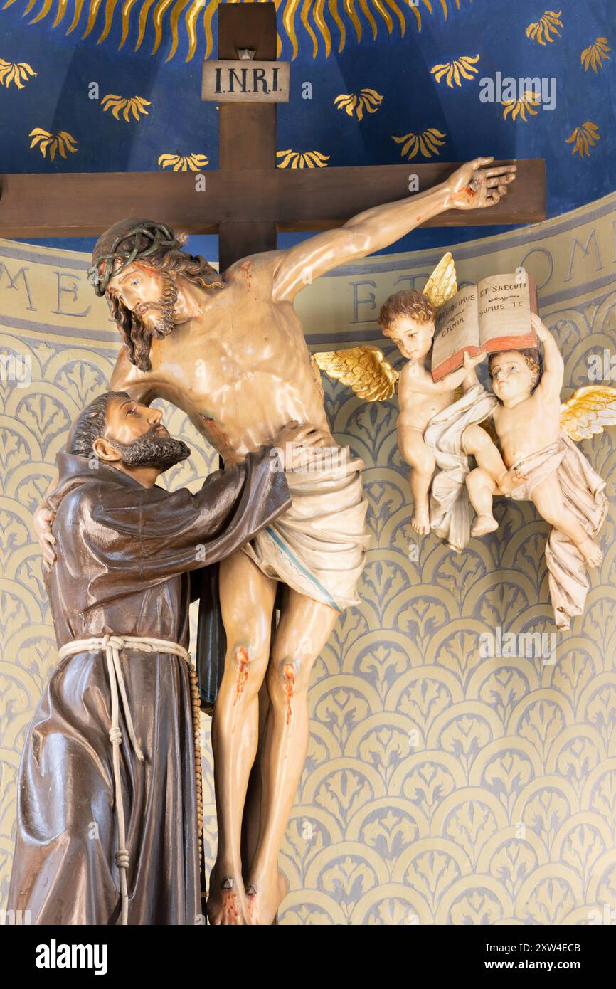 MILANO, ITALIA - 6 MARZO 2024: Statua in policromo scolpita di San Francesco d'Assisi con Gesù sulla croce nella chiesa del Sacro cuore Foto Stock