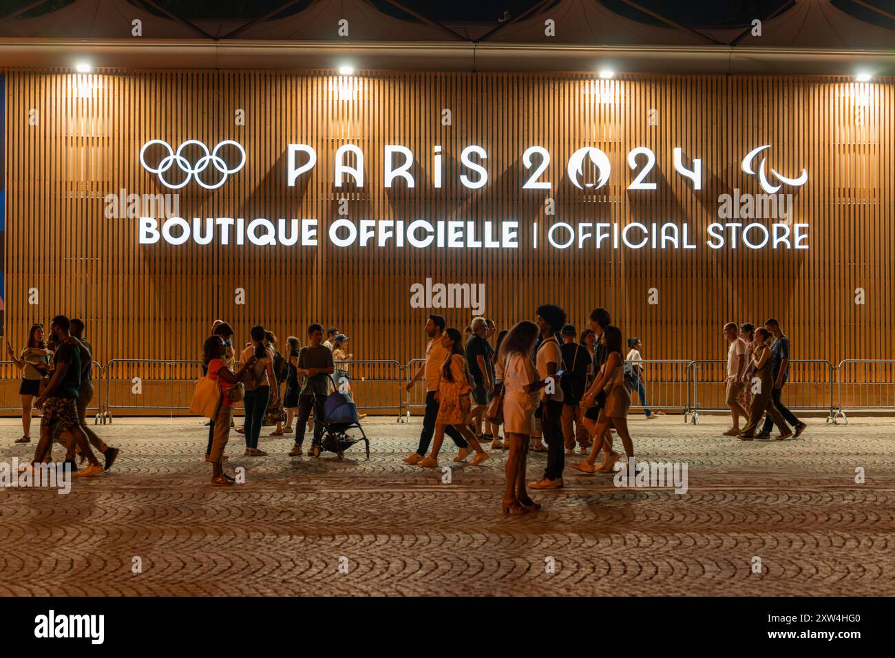 Parigi, Francia - 10 agosto 2024: La folla passa davanti alla boutique ufficiale Olympic Pop-up sugli Champs-Elysees di notte Foto Stock