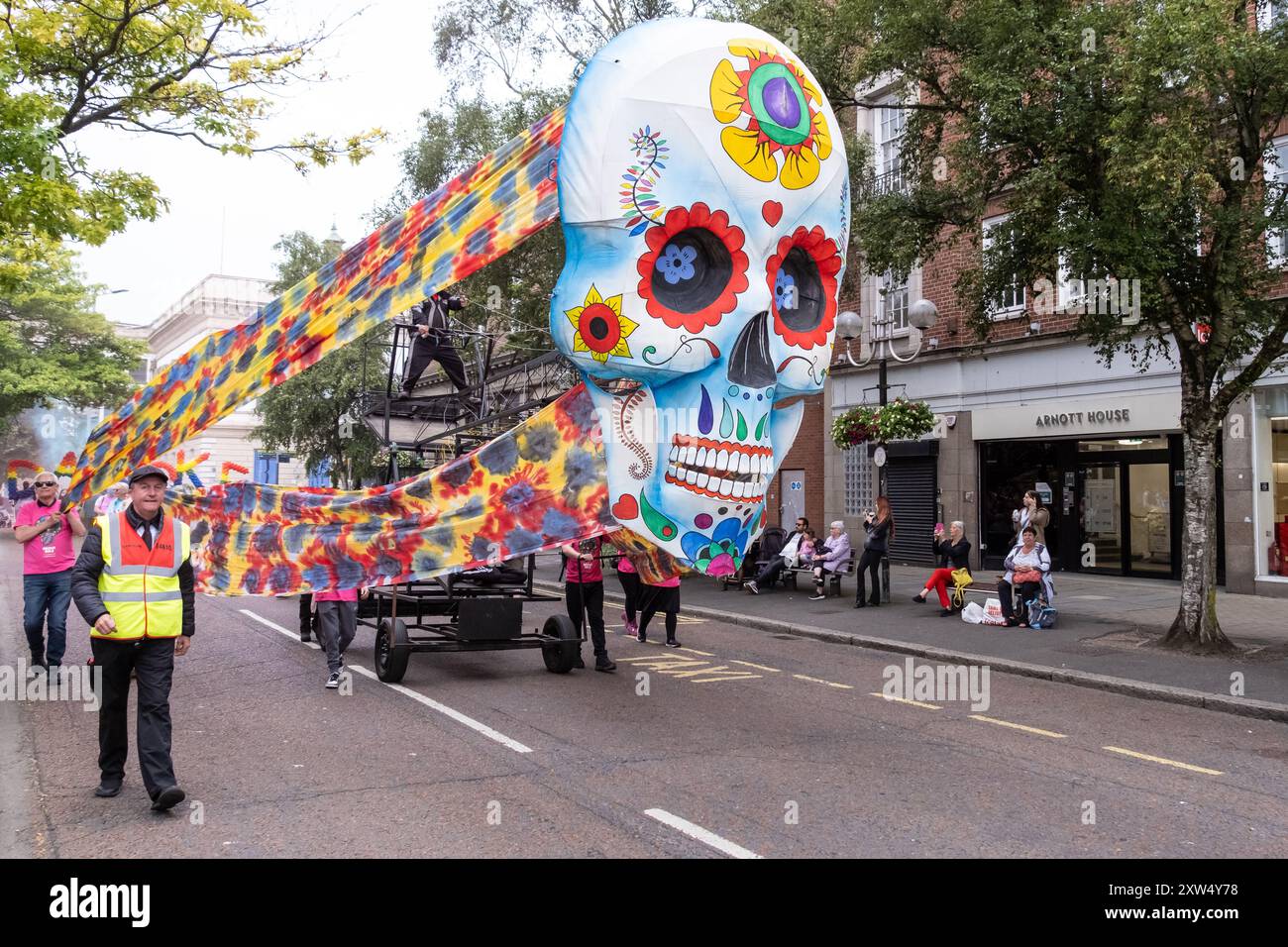 Annuale Belfast Mela Carnival Parade - gigantesco colorato il teschio messicano Day of the Dead di fronte al galleggiante nel centro della città. Belfast, Regno Unito - 17 agosto 2024 Foto Stock