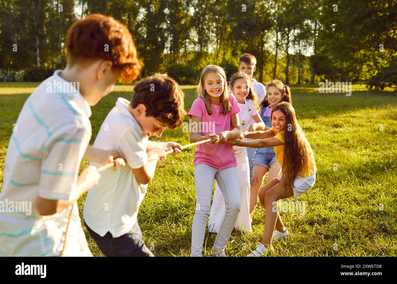 Gruppo di bambini felici e felici sorridenti che giocano insieme nel tiro alla fune nel parco. Foto Stock