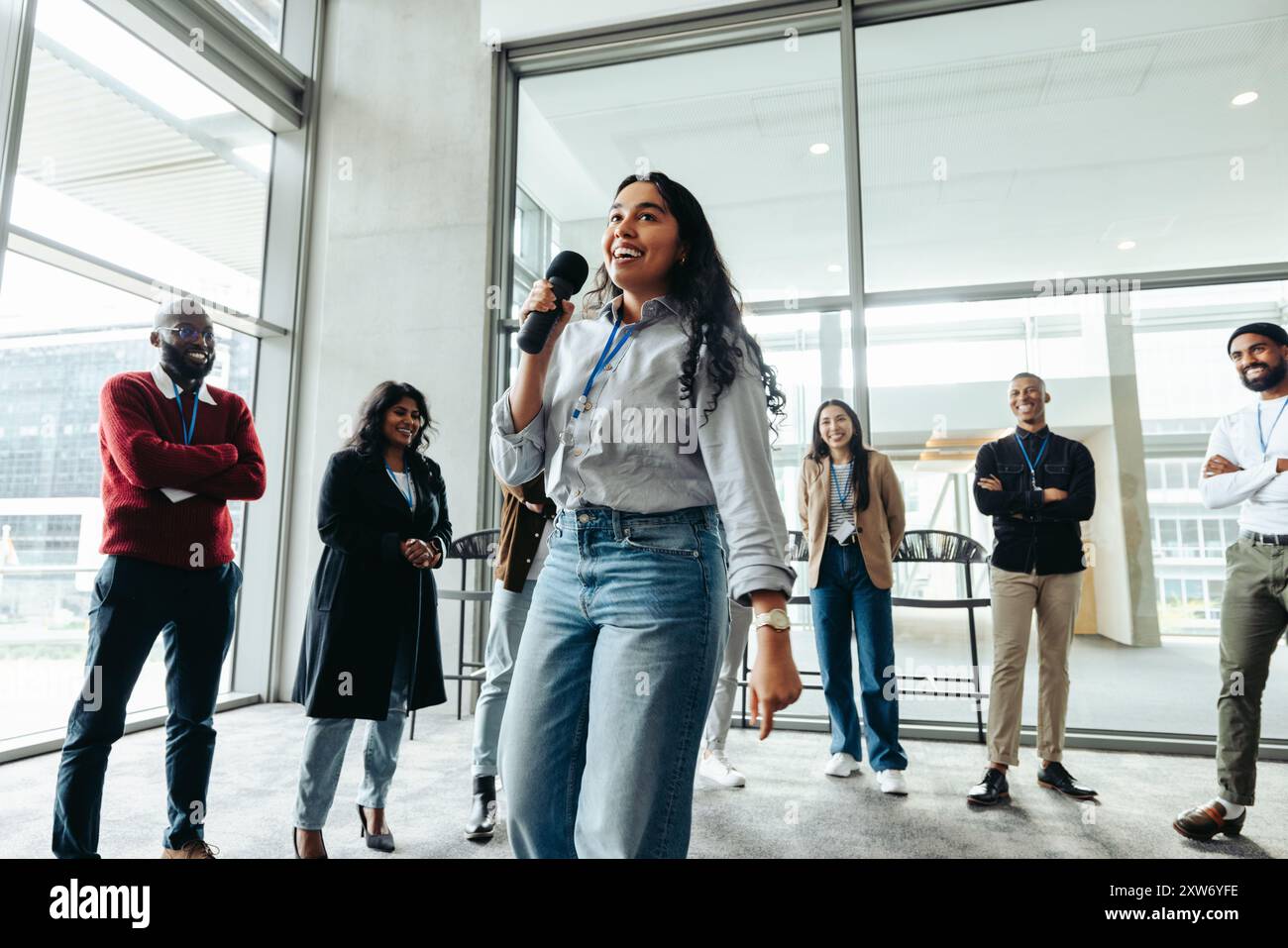 Gruppo di giovani dipendenti aziendali impegnati in un evento di team building con un relatore dinamico. Team diversificato in un ambiente moderno. Foto Stock