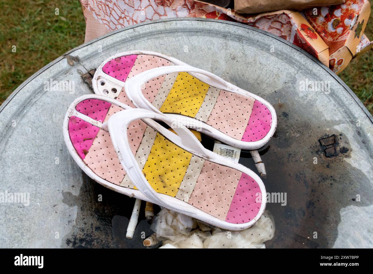 ciabattine in plastica colorata usate gettate sul coperchio di un cestino della spazzatura Foto Stock