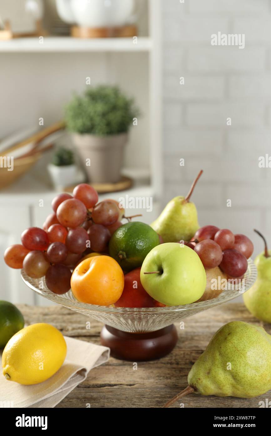 Vaso di vetro con frutta fresca diversa su un tavolo di legno Foto Stock