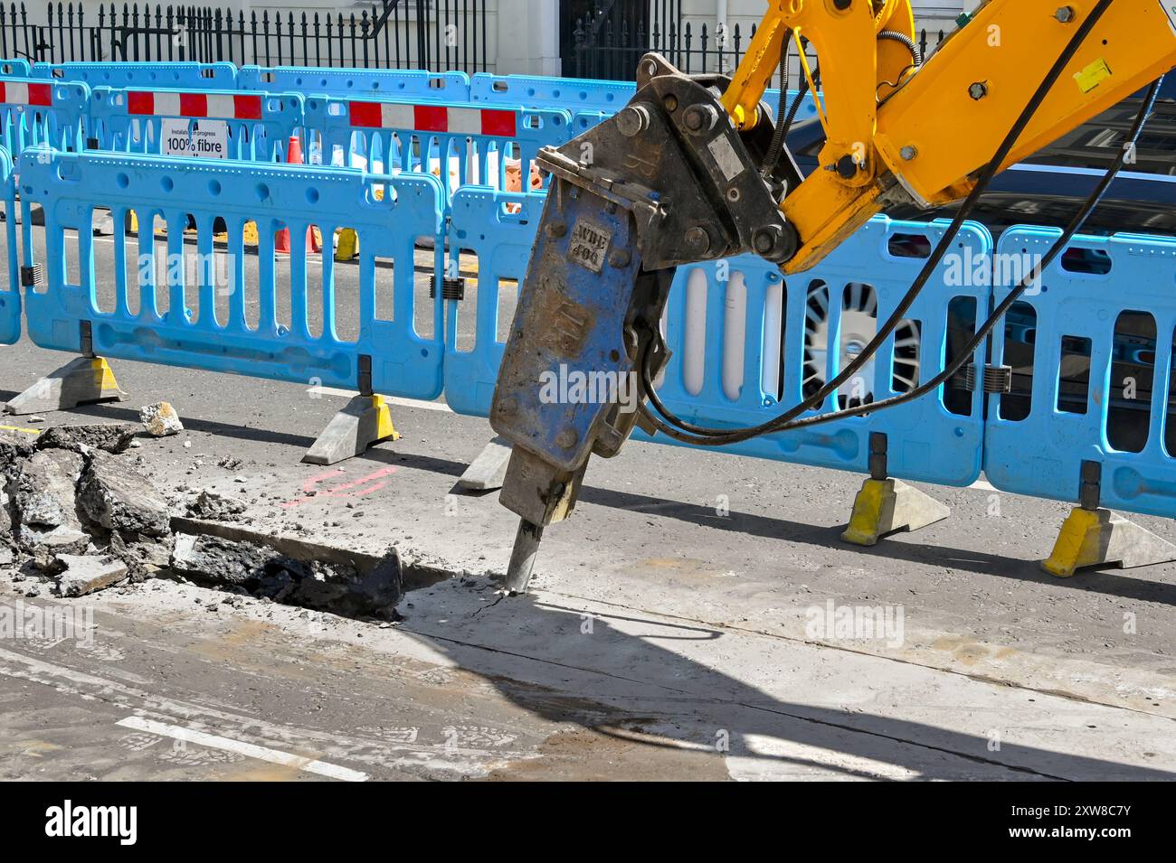 Londra, Inghilterra, Regno Unito - 21 giugno 2022: Escavatore con attacco pneumatico utilizzato per scomporre la superficie stradale di una strada nel centro di Londra Foto Stock