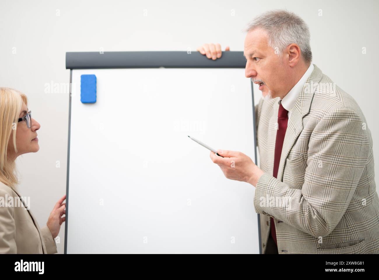 Uomo d'affari che mostra i dati su una lavagna vuota durante una riunione Foto Stock