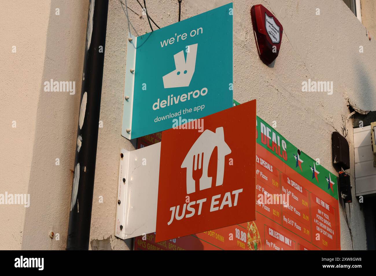 I cartelli Deliveroo & Just Eat si trovano fuori da un fast food di Brighton Foto Stock