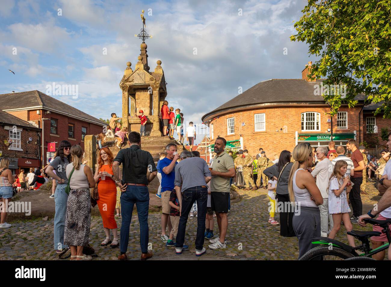 Persone che si mescolano al sole della sera a Lymm Cross durante il Lymm Food Festival 2024 Foto Stock