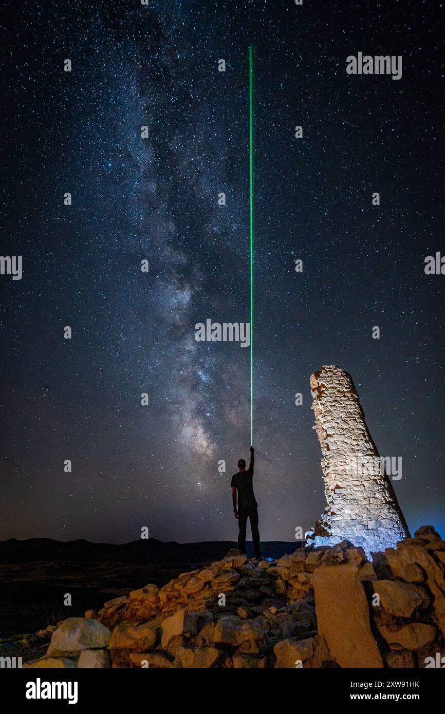 Uomo che indica la via Lattea con laser verde nel villaggio iberico di San Pedro Oliete Teruel Foto Stock