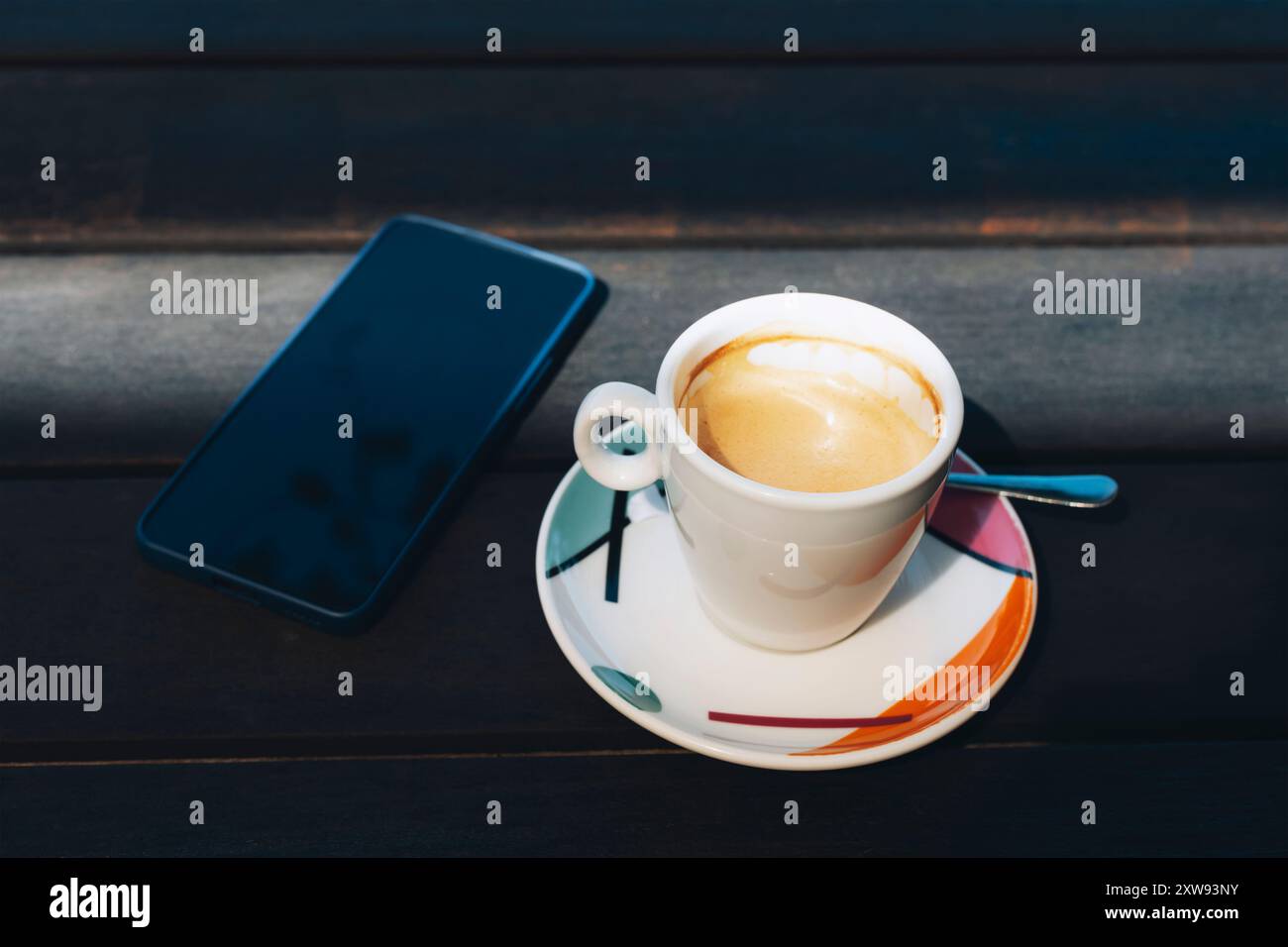 Una tazza di caffè e un telefono cellulare su un tavolo di legno, da vicino. Foto Stock
