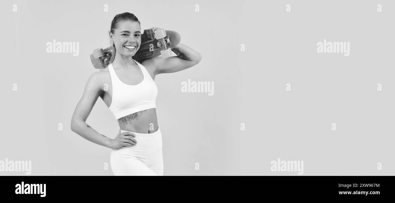 Godersi la vita a bordo del penny. Skater ragazza sfondo giallo. Felice atletica ragazza tenere pennyboard. Donna ritratto isolato volto, banner con mock up Foto Stock