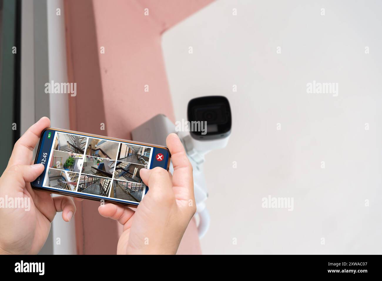 Tecnico professionista cctv che lavora. Persona che tiene a mano lo smartphone con più viste delle sedi degli uffici. Sorveglianza, tecnologia moderna b Foto Stock