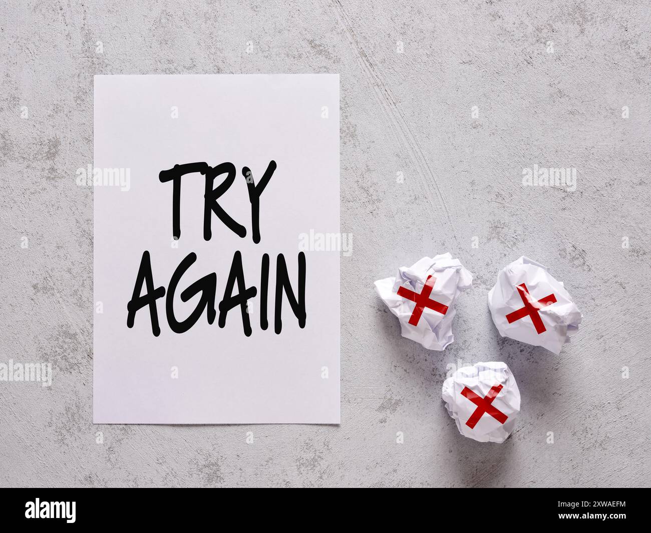 Messaggio motivazionale di incoraggiamento a provare di nuovo e a non arrendersi. Il messaggio Riprova su un foglio bianco accanto ai fogli arricciati con x Foto Stock