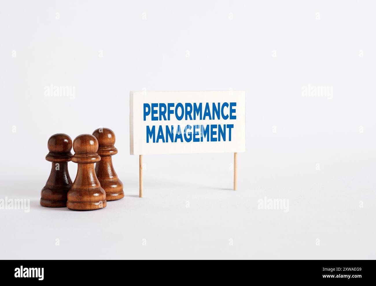 Gestione, miglioramento o sviluppo delle prestazioni nel business. Pedine degli scacchi in piedi accanto a uno striscione con la parola "performance management". Foto Stock