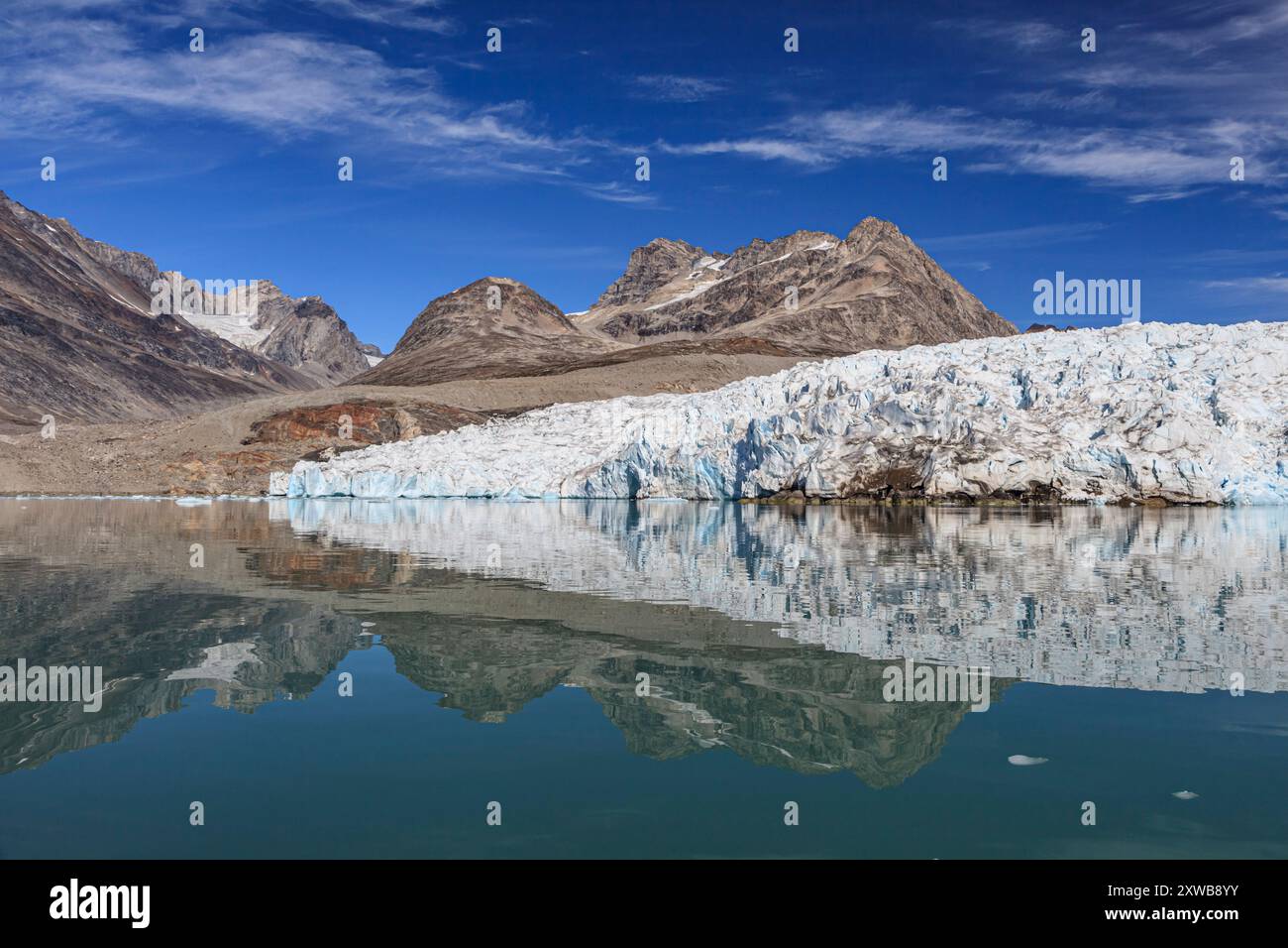 Riflesso del ghiacciaio, degli iceberg e delle montagne in un fiordo remoto, della Groenlandia orientale e della Groenlandia Foto Stock