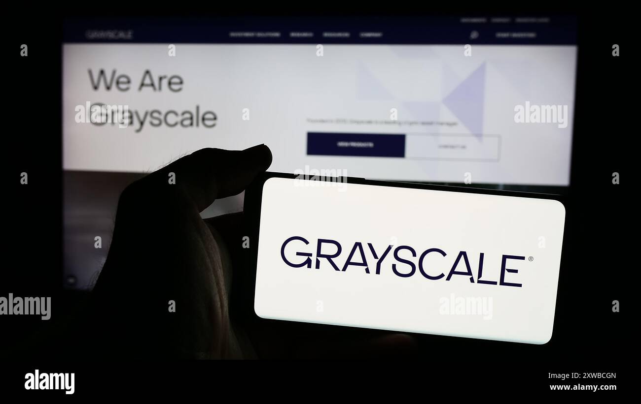 Persona che detiene uno smartphone con il logo della società statunitense di gestione cripto Grayscale Investments LLC davanti al sito web. Mettere a fuoco il display del telefono. Foto Stock