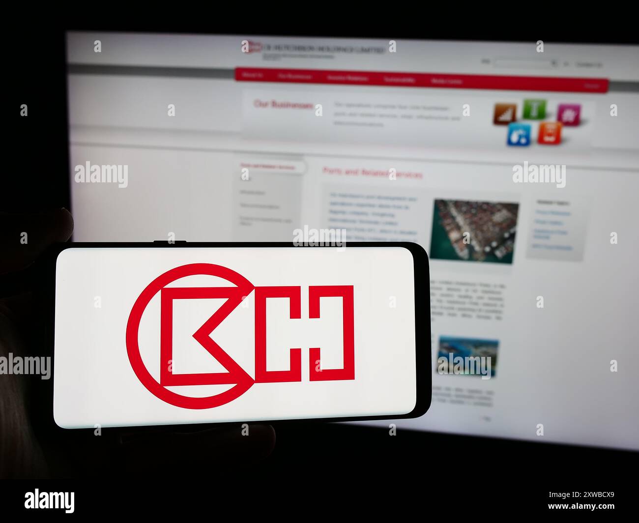 Persona che detiene uno smartphone con il logo della società di Hong Kong CK Hutchison Holdings Limited davanti al sito Web. Mettere a fuoco il display del telefono. Foto Stock