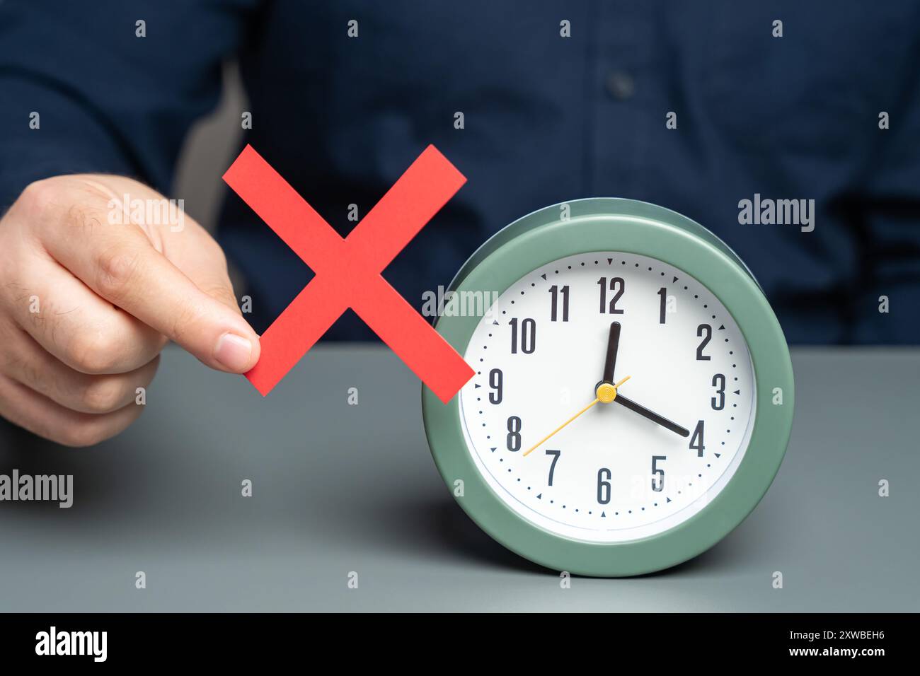 Un uomo ha un cartello rosso di divieto vicino all'orologio. Divieto di cambio orario. Estate e inverno. Leggi, regolamenti Foto Stock