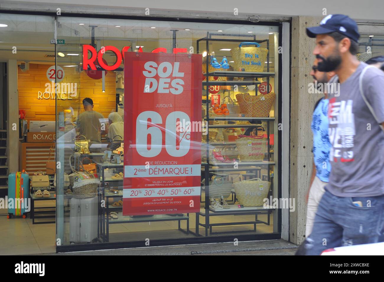 Tunisi. 18 agosto 2024. La gente passa davanti a una finestra con la parola "sconto" nel centro di Tunisi, Tunisia, il 18 agosto 2024. La stagione estiva degli sconti in Tunisia va dall'inizio di agosto alla metà di settembre di ogni anno. Crediti: Adel Ezzine/Xinhua/Alamy Live News Foto Stock