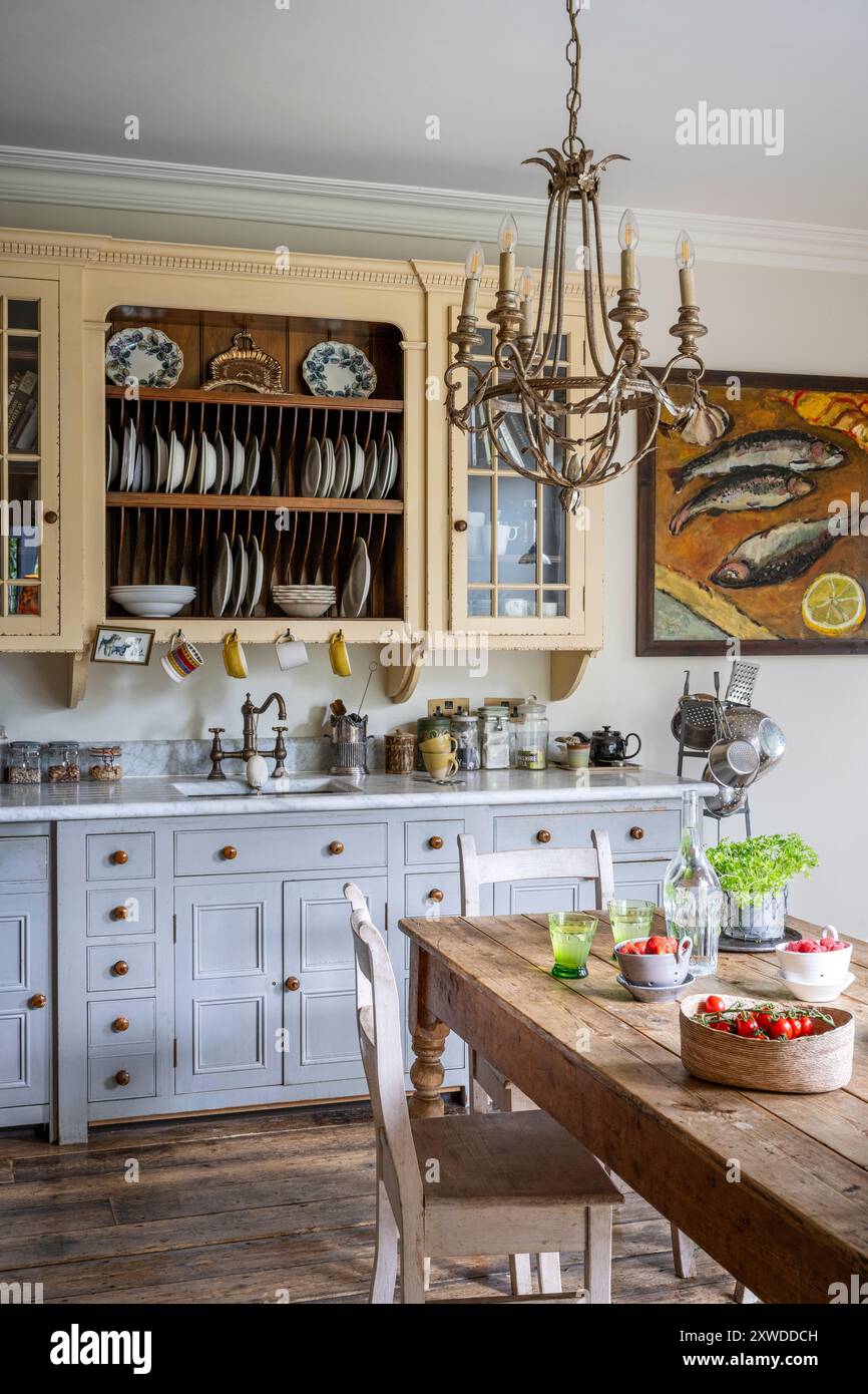 Candelabra e pittura di pesce in cucina disegnata da Chalon con piani di lavoro in marmo di Carrara nella casa di Wimbledon, a sud-ovest di Londra, Inghilterra, Regno Unito. Foto Stock